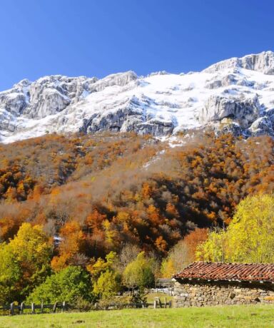 Cabaña de piedra con montañas nevadas al fondo